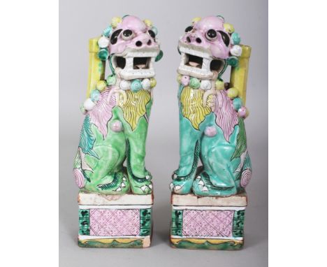 A PAIR OF 18TH CENTURY CHINESE BUDDHISTIC LION PORCELAIN JOSS STICK HOLDERS, each supported on a rectangular plinth and appli