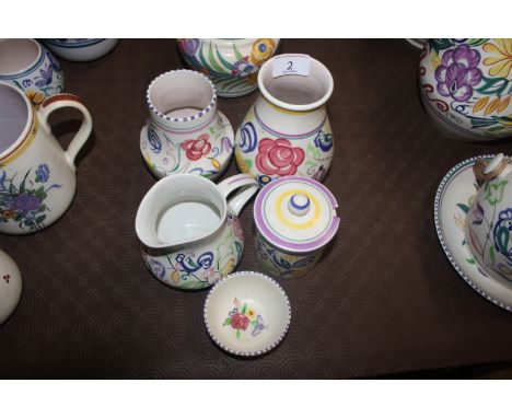A Poole pottery preserve jar and cover; two bird decorated vases; a floral decorated jug and a shallow bowl with rose and but