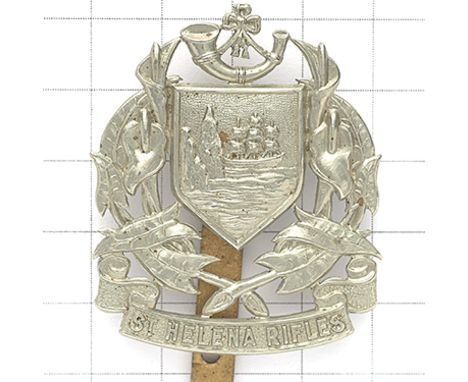 St. Helena Rifles white metal cap badge circa 1914-46. Die-stamped strung bugle on shield flanked by floral sprays on title s