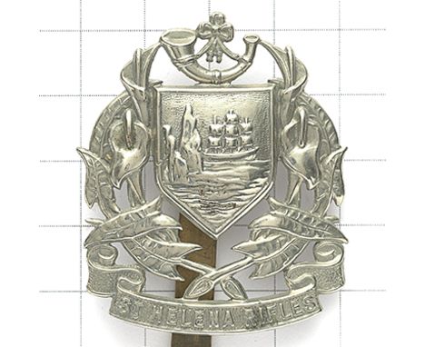 St. Helena Rifles white metal cap badge circa 1914-46. Die-stamped strung bugle on shield flanked by floral sprays on title s