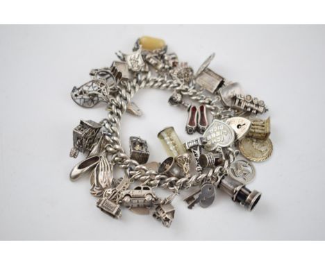 Heavy silver charm bracelet with charms to include a miners lamp, Blackpool Tower, slippers and others, 121.5 grams.  