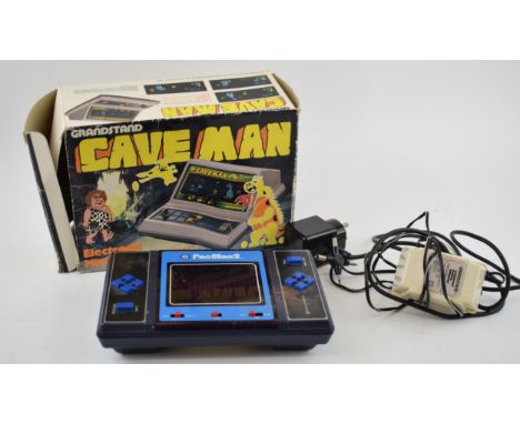 Vintage electronic toys to include boxed Grandstand Cave Man and Pac Man 2. (2)  In good used condition with some wear commen