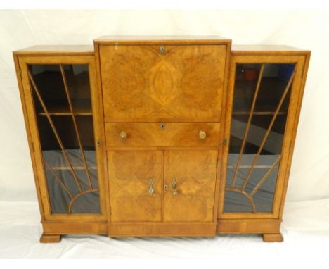 FIGURED WALNUT DISPLAY CABINET
with a central fall flap revealing a fitted interior above a drawer and a pair of cupboard doo