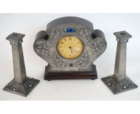 ART NOUVEAU CLOCK GARNITURE
with a shaped case applied with tin and embossed with flowers and hardstones, around a circular c