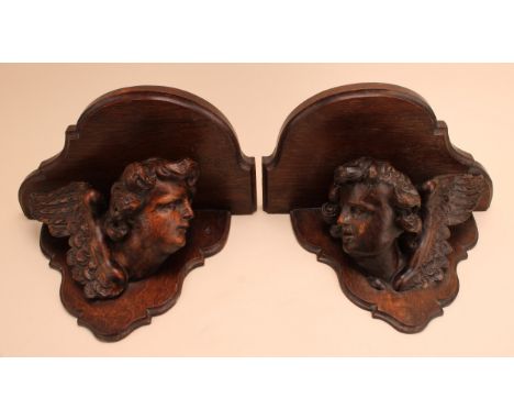 A pair of 19th century wall brackets, each with shaped serpentine plateau above a carved winged putto corbel, 32cm wide
