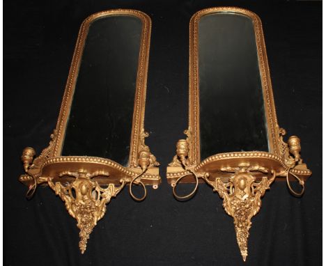 A pair of late 19th century giltwood and gesso pier girandole looking glasses, each with an arched mirror plate, 127cm high, 