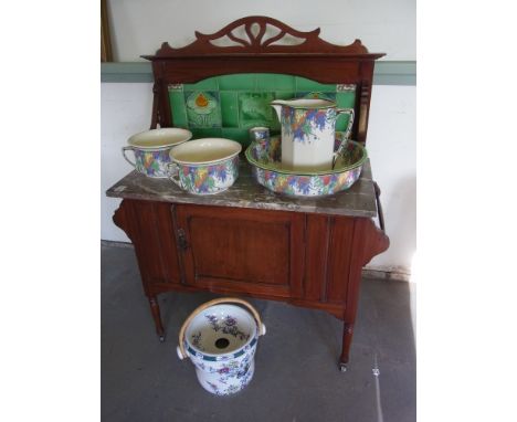 An Edwardian tile back mahogany washstand with a marble top and a Doulton five piece jug and bowl set with a Doulton slop buc