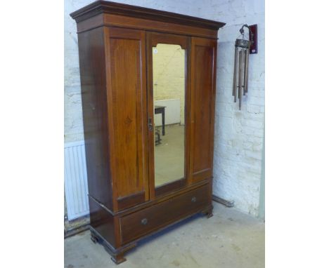 An Edwardian inlaid mahogany wardrobe fitted with a single mirrored door over a full width drawer standing on shaped bracket 