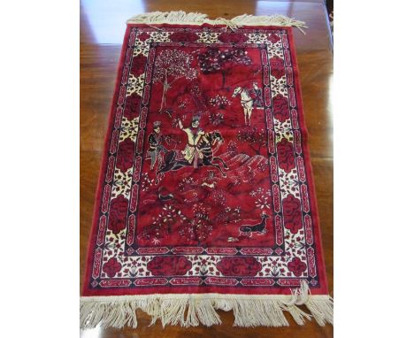A small silk rug with a red field decorated with a Hunting scene - 1.2 m x 69 cm 