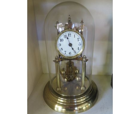 A brass anniversary clock in glass dome with white enamel face with Roman numerals - case height 30cm