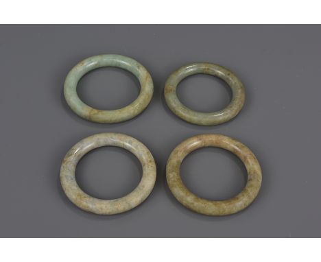 A group of four Chinese 18/19th century jade bangles. 6.5cm - 7.5cm diameters (4)