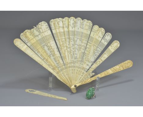 A Chinese ivory fan (damaged) together with a carved jade stone mounted in a silver colour ring. (2)