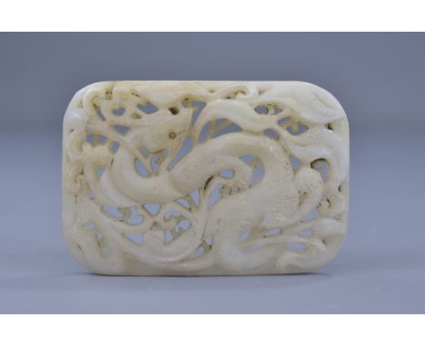 A Chinese Ming or later white jade belt buckle carved through with dragon decoration. 8cm x 5.5cm