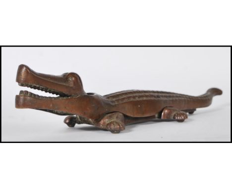 A vintage mid 20th Century cast brass nutcracker in the form of a crocodile, with metamorphic action. Measures 38 cm long.