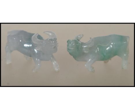 A pair of Chinese jade carved figurines of small proportions in the form of water buffalos. One of the buffalos has a leg mis