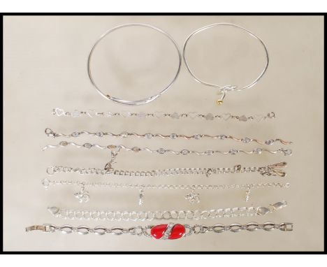 A selection of stamped silver bracelets to include two spacer bracelets set with oval cut white stones, a cross over design b