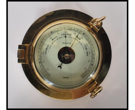 A contemporary 20th Century brass cased wall mounted ships barometer in the form of a porthole. Stamped Nauticalia to the fac