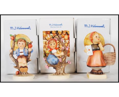 A group of three German Goebel Hummel figurines in boxes to include Herbet Apple tree boy, Fruhling apple tree girl, and a fi