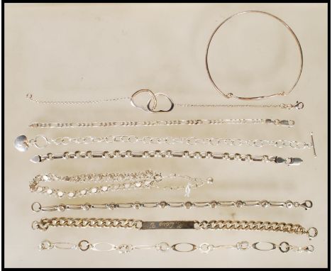 A selection of silver bracelets to include a spacer bracelet having a lobster claw clasp, oval and round decorated bracelet, 