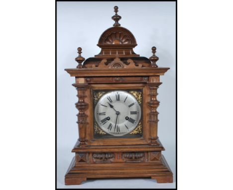  A late 19th / early 20th Century walnut cased brass faced eight day mantel clock, the case of architectural form, brass face