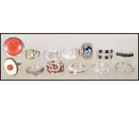 A selection of stamped 925 rings to include an openwork ring set with an oval cut green stone, CZ rings, a banded ring set wi