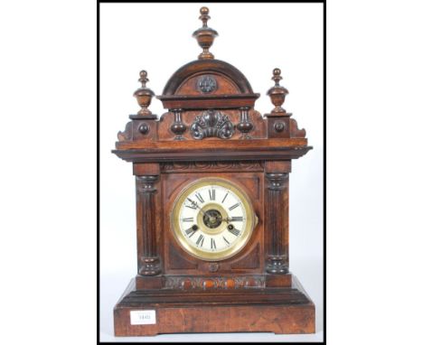 An early 20th century Hamburg America Clock Company walnut cased mantel clock, the arched shell carved and fluted pilaster ca
