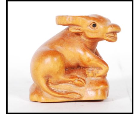 A detailed carved boxwood netsuke figure in the form of a laying yak. Measures 4cm tall by 4.5cm wide.&nbsp;