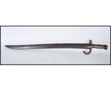 A French 19th century 'Chassepot' pattern 1874 rifle bayonet and scabbard, having a brass ribbed handle, shaped penny end ste