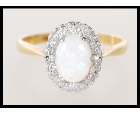 A stamped 18ct gold ladies ring set with an oval opal cabochon having a halo of white stones. Weight 3.6g. Size P.