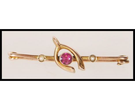 A 19th Century Victorian brooch stamped 9ct gold moulded as a wishbone set with a central faceted cut amethyst flanked by see