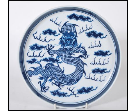 A 19th Century Chinese ceramic plate being hand painted in blue depicting a five toed dragon to the plate, the interior of th