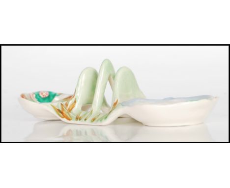 An early 20th Century Art Deco Clarice Cliff toast rack, decorated with stylised foliage in blue, green and pink, shape numbe