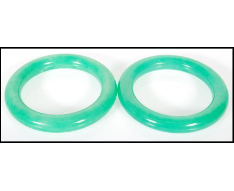 A pair of 20th Century Chinese jade type slave bangles of typical form. Interior diameter 6cm.&nbsp;