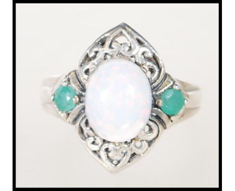 A stamped 925 silver ladies dress ring set with an opal flanked by two green stones on a decorative pierced mount. Ring size 