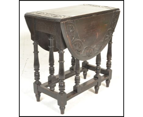 A early 20th Century carved oak drop leaf dining table being raised on turned legs united by stretcher having drop leaves rai