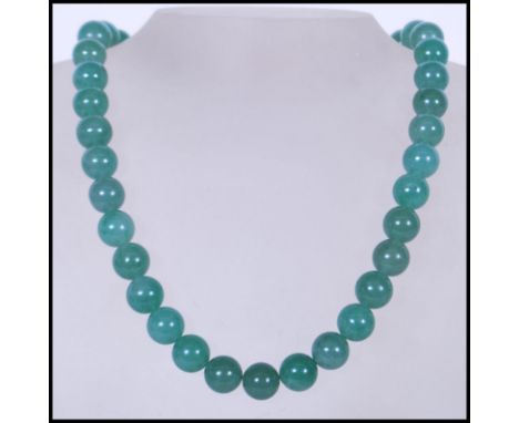 A 20th Century Chinese beaded and knotted green jade necklace, with silver white metal lobster clasp