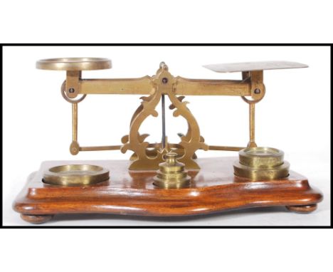 A set of late 19th / early 20th Century brass postal scales, with a selection of weights&nbsp; within a wooden base.