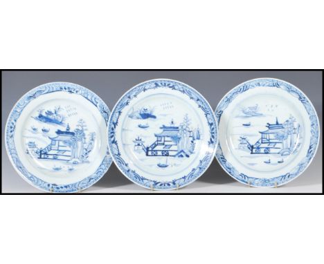 A group of three Chinese 18th Century ceramic blue and white plates all hand painted with a pagoda water scene, the rims deco