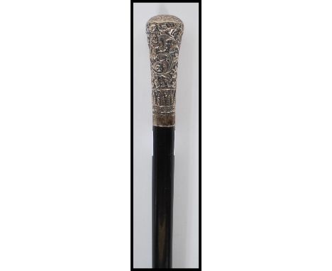 A late 19th Century / 20th Century Victorian promenade walking stick cane having a silver knop with repousse scrolled foliate