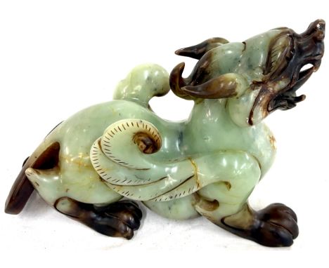 A large Chinese possibly jade dragon, in green &amp; brown colours, in recoiled stance with snarling mouth, approximate measu