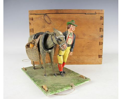 A mid 20th century continental folk art model of a man and his donkey, the donkeys head with nodding action, within pine box 