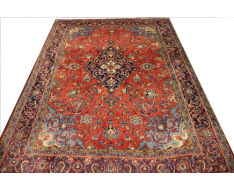 A Persian Sarouk wool carpet, worked with an all over foliate design against a red ground, 306cm x 216cm