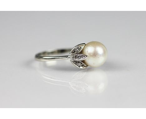 A pearl and diamond ring, the central untested pearl (measuring 8.5mm diameter), with diamond set foliate shoulder and white 
