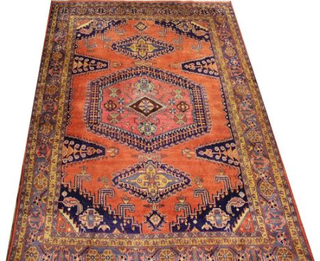 A Caucasian hand woven wool carpet, worked with geometric motifs against a red ground, 342cm x 231cm