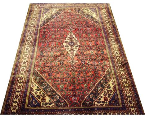 A Persian Hamadan wool carpet, worked with an all over foliate design against a red ground with blue ground striped borders, 