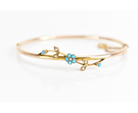 A 10ct gold bangle inset with turquoise and seed pearls, having a floral design with seven turquoises and five seed pearls on
