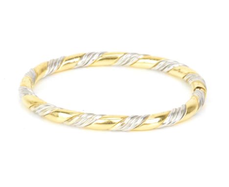 An 18ct gold bi-coloured bangle, having a gadrooned design alternating in yellow and white gold, stamped 750, approx inner ci