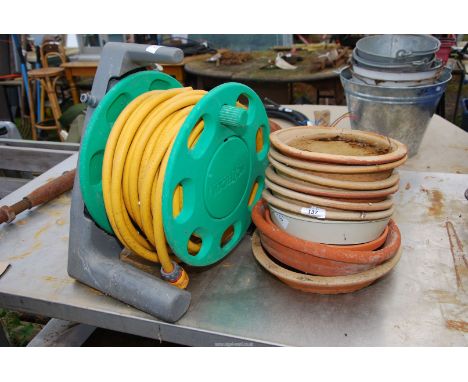 A quantity of terracotta saucers and a hose on reel.