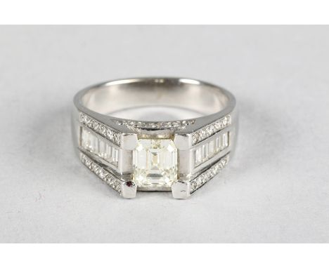 18 carat white gold diamond ring, central 1 carat emerald cut diamond, flanked either side by five baggette cut diamonds and 