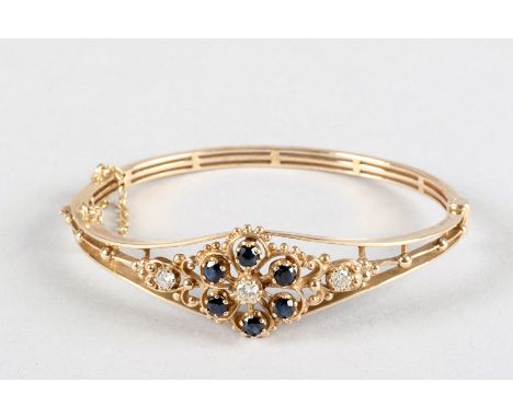 Ladies 9 carat yellow gold stiff bangle, pierced floral design set with diamonds and sapphires, total weight 13 grams 